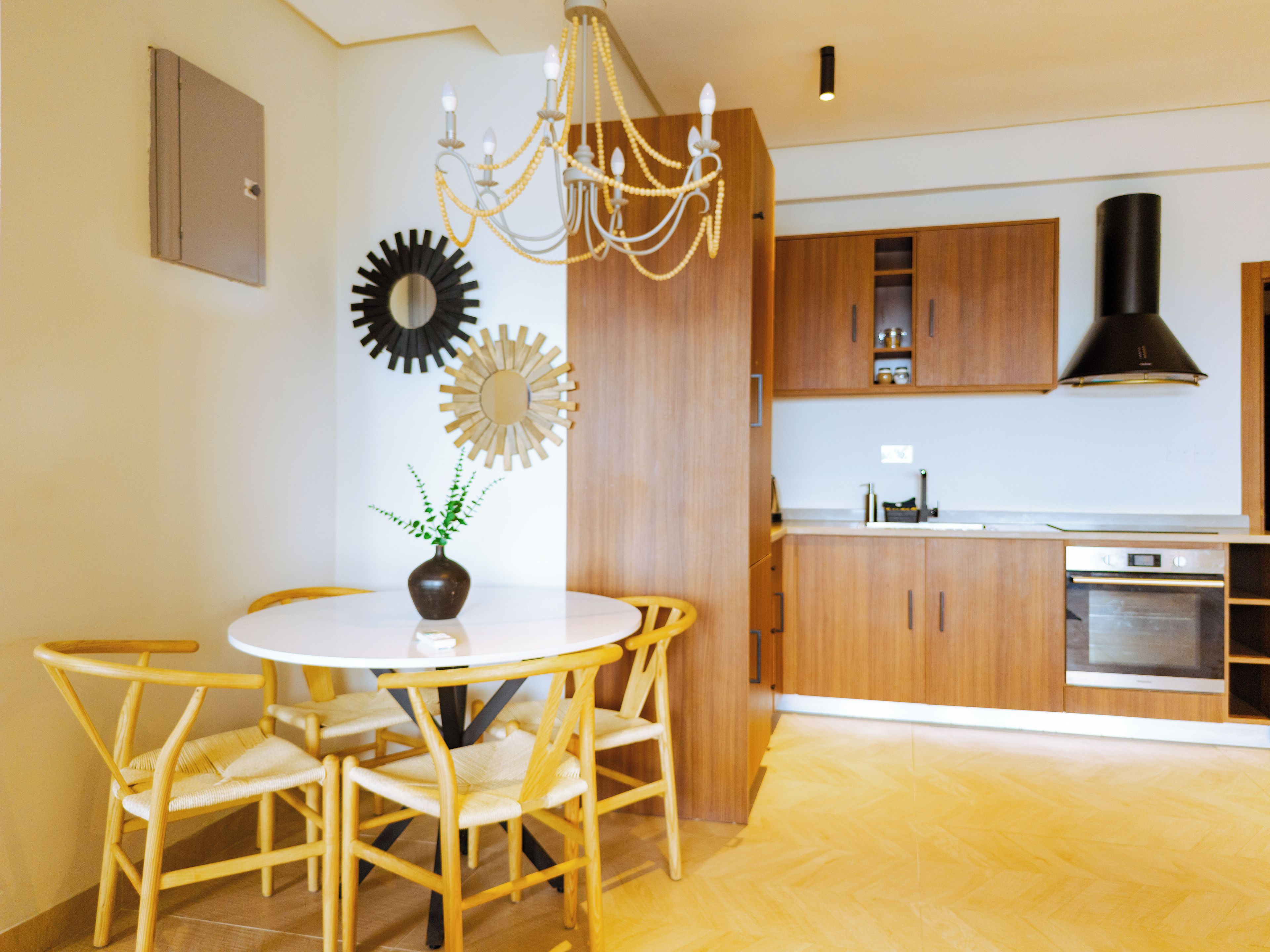 A modern kitchen with wooden cabinets, a built-in oven, and a chandelier.