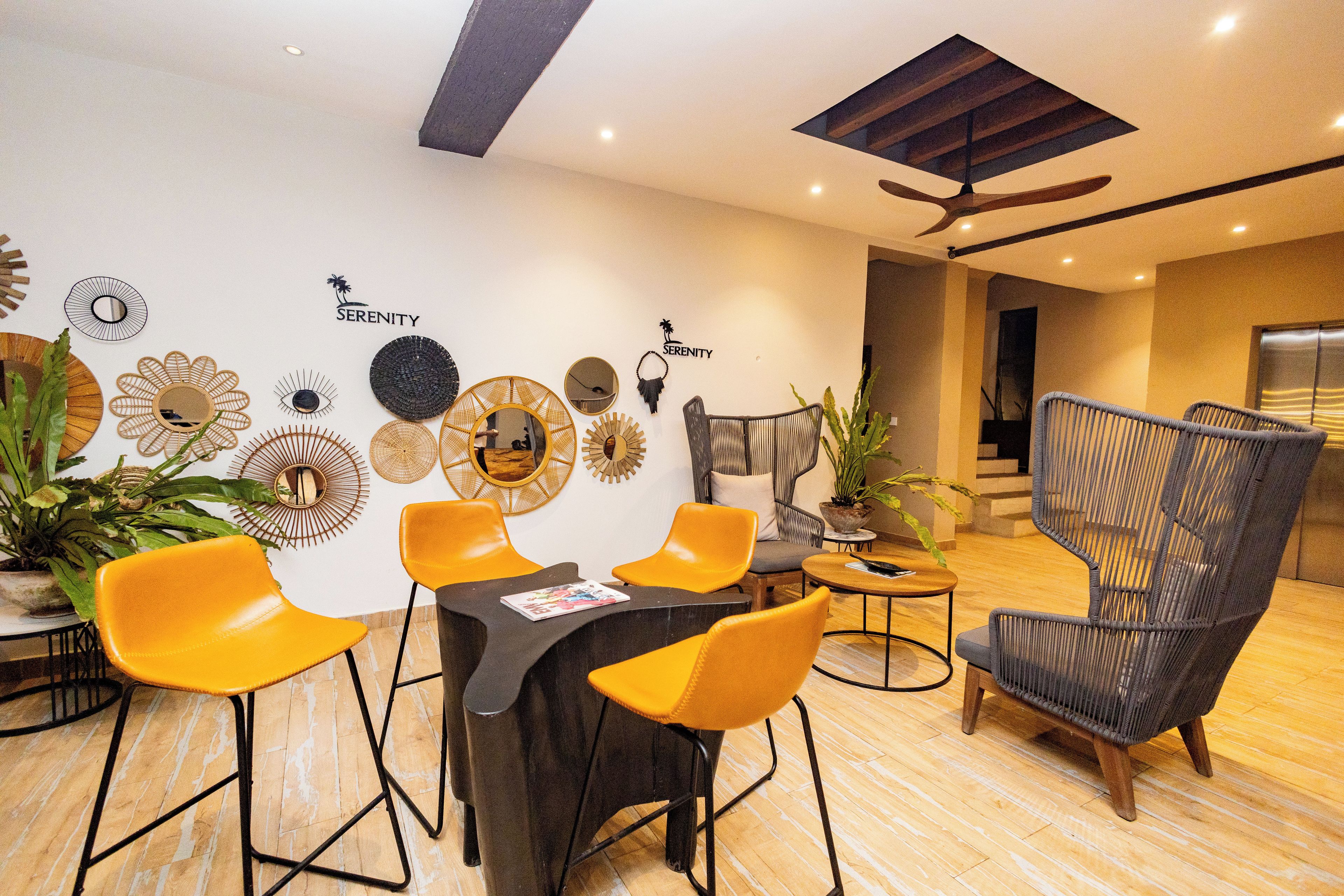 A modern dining area with a round table, yellow chairs, and a ceiling fan.