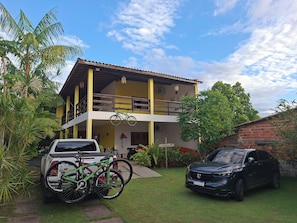 A two-story building with a balcony, a parked bicycle, and a car in the driveway. - Pousada Pura Vida (Barreirinhas)