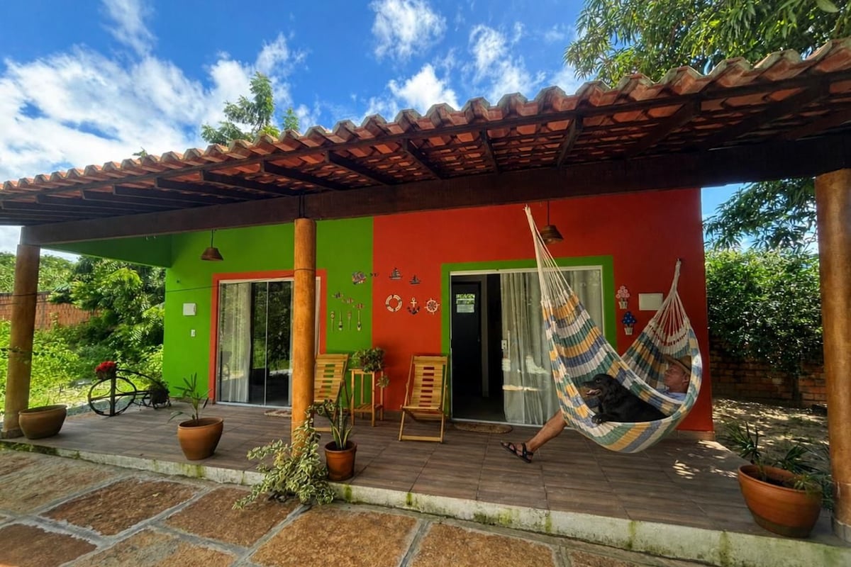 A colorful building with a porch, potted plants, and a hammock.