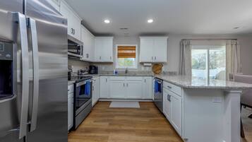 Una cocina moderna con electrodomésticos de acero inoxidable, armarios blancos y encimera de granito.