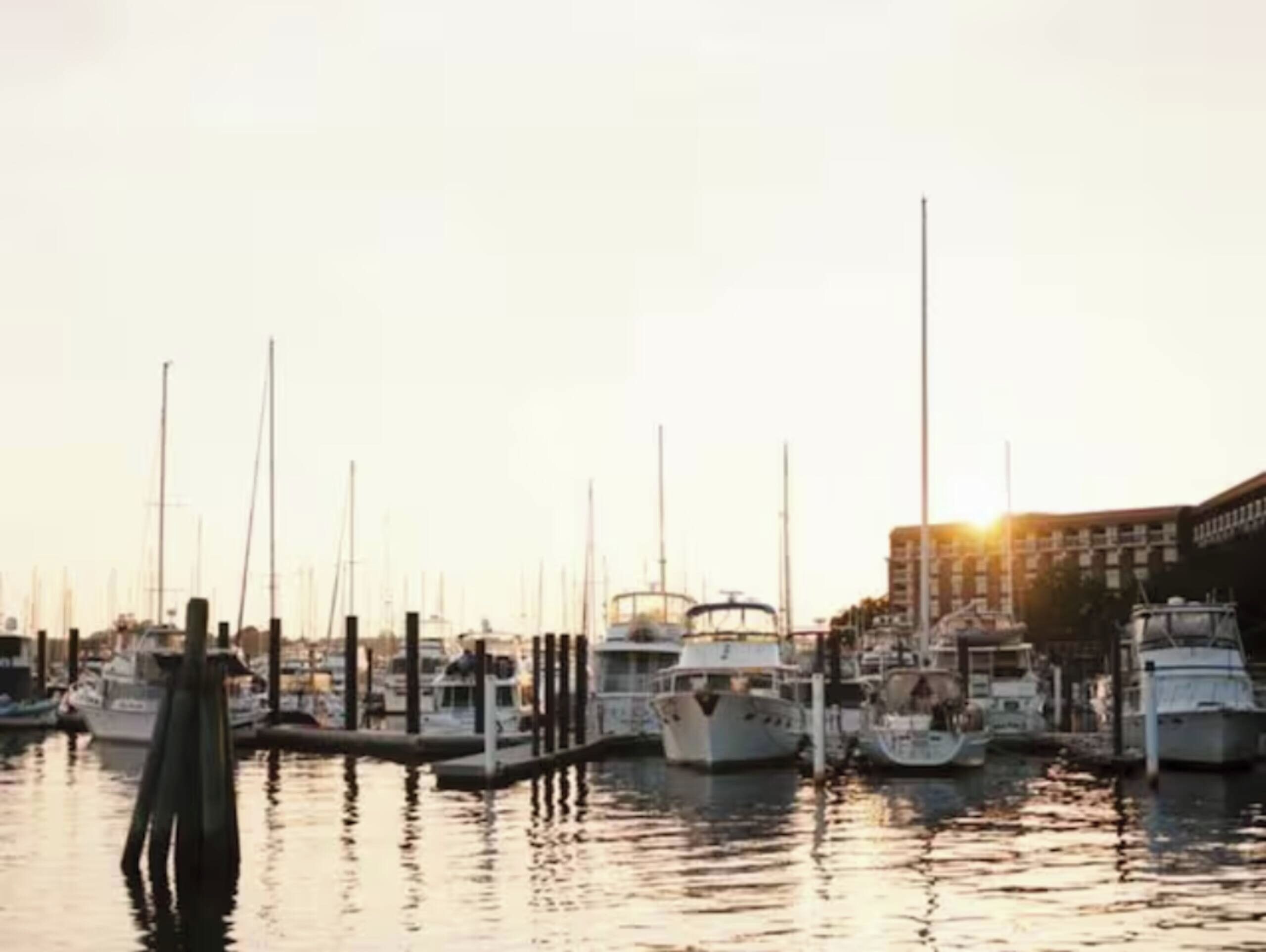Un port de plaisance où des bateaux sont amarrés aux quais, entouré d’immeubles.