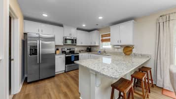 A modern kitchen with stainless steel appliances, white cabinetry, and a granite countertop.