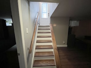 A staircase leading to a door with a window, wooden steps, and a handrail.