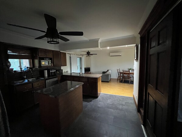 A kitchen with a central island, a dining area with a table and chairs, and a ceiling fan.