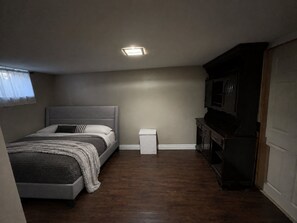 A bedroom with a bed, a nightstand, a dresser, and a television. - Large 5-bedroom Home Near 401.  Ideal for Work Crews & Families. (Cornwall)