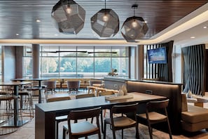 A modern dining area with multiple seating options, including tables and booths, and large windows providing a view of the outdoors. - Springhill Suites By Marriott Columbia North (Columbia)