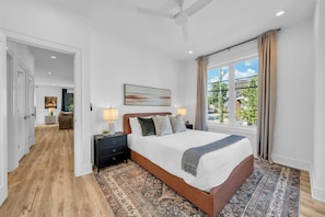 A hotel room with a large bed, a nightstand, a window with curtains, and a view of the outside. - Nashville Hideaway | Rooftop Hot Tub & Fire Pit (Nashville)