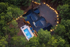 A residential property with a swimming pool, multiple buildings, and a surrounding wooded area. - NEW ! Bear Lake Lodge - Private pond/Hidden speakeasy/pool/pedal boat/kayaks (Broken Bow)