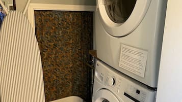 A laundry area with stacked washing machines, a drying rack, and a laundry basket.