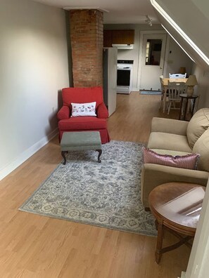 A living room with a red armchair, a beige sofa, and a patterned rug. - Cozy 1-bedroom apartment in peaceful Wilton (Wilton)