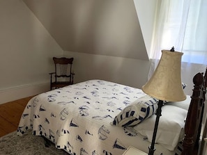 A bedroom with a bed, a nightstand, a lamp, a chair, and a window with curtains. - Cozy 1-bedroom apartment in peaceful Wilton (Wilton)