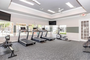 Un gimnasio con cintas de correr, una máquina elíptica y un banco para pesas.