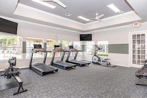 Un gimnasio con cintas de correr, una máquina elíptica y un banco para pesas.