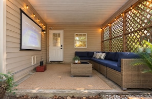 A covered porch with a sofa, a small table, and a door. - 5BR , Sleeps 14 , Central to Downtown & Tybee (Savannah)
