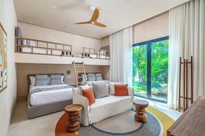 A modern hotel room with a bunk bed, a sofa, a wooden ladder, a ceiling fan, and a large window with a view of greenery. - Beachfront 5BR Villa w/ Pool, big garden, Ocean Views & Premier Golf Membership (Punta de Mita)