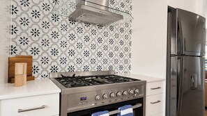 A kitchen with a gas stove, oven, and a stainless steel refrigerator. - Fingal Tide House - Spacious 3BR Beachside Getaway (Fingal Bay)
