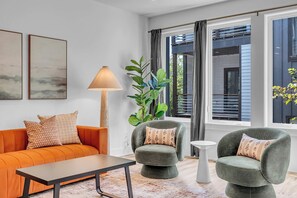 A modern living room with a sofa, two armchairs, a coffee table, a floor lamp, and a large window with curtains. - Nashville Hideaway | Amazing Rooftop Patio & Views (Nashville)
