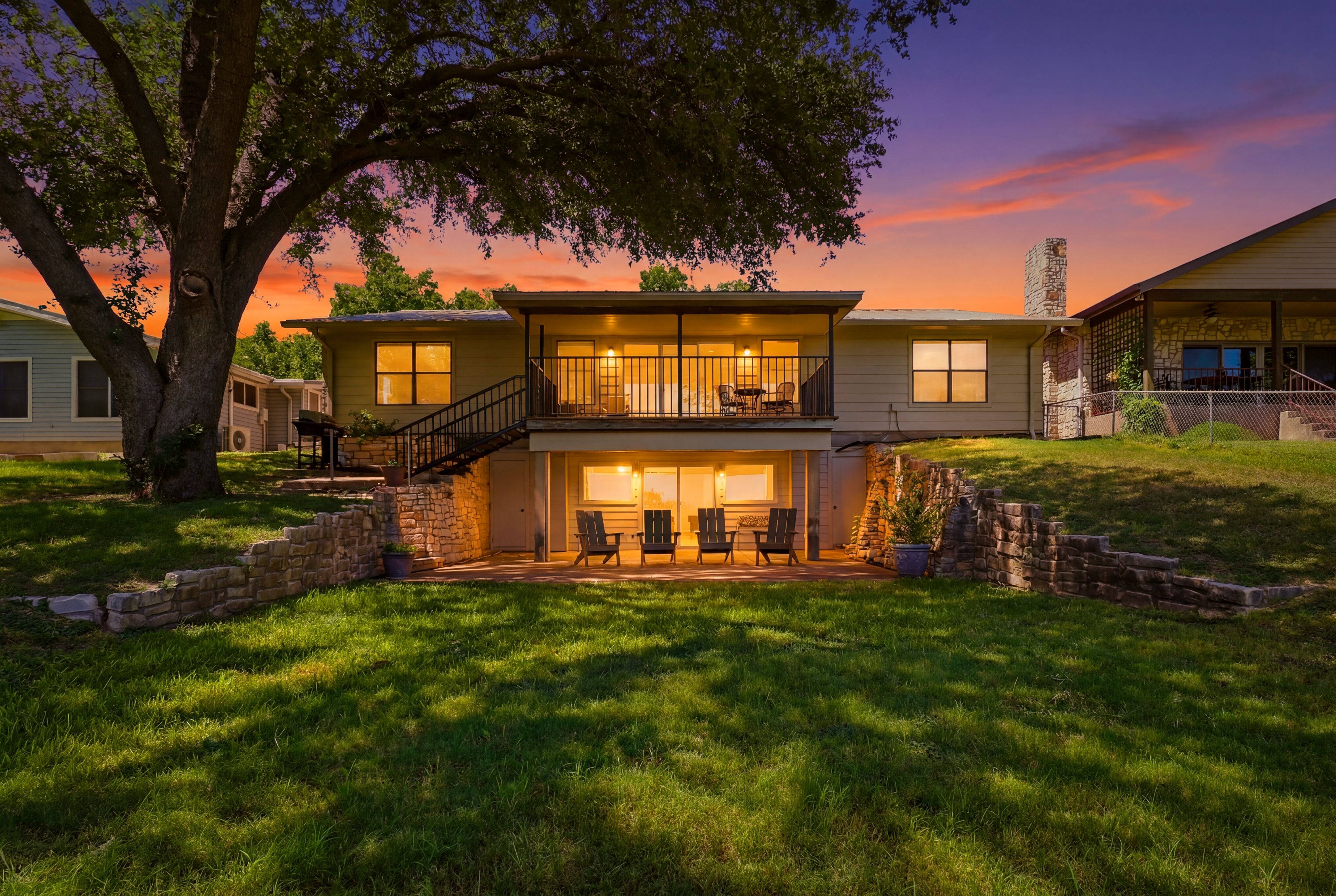 A two-story house with a balcony, a stone staircase, and a well-maintained lawn.
