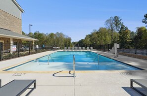 A swimming pool with a lifeguard station, surrounded by a fence, and a building with a covered area. - Landing Stylish 1bd, Clubhouse, Gym (Raleigh)