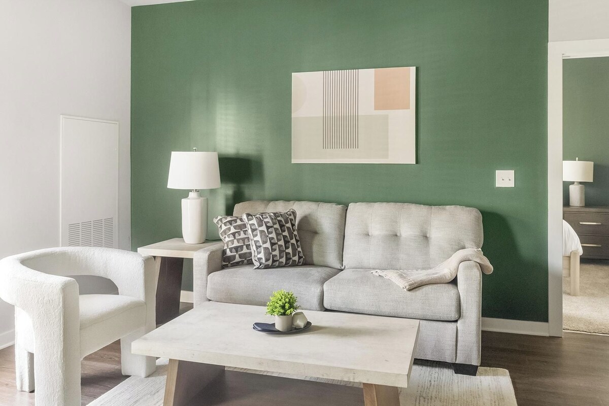 A living room with a sofa, a coffee table, a lamp, and a wall art piece.
