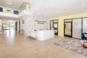 Eine geräumige Lobby mit einer Rezeption, einer Marmorwand und Blick auf die oberen Etagen.
