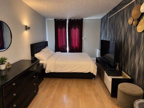 A bedroom with a bed, dresser, TV, and a wall-mounted shelf. - aroma house (Tulle)