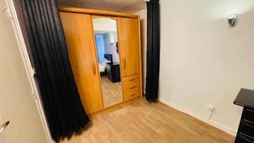 A room with a wooden wardrobe, a mirror, and a black dresser.