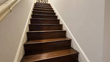 A wooden staircase with white walls and a decorative wall panel at the top.