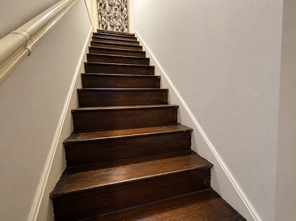 A wooden staircase with white walls and a decorative wall panel at the top. - aroma house (Tulle)