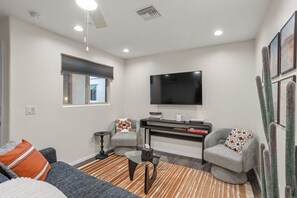 Ein modernes Wohnzimmer mit Fernseher, Sofa, Couchtisch und Bücherregal.