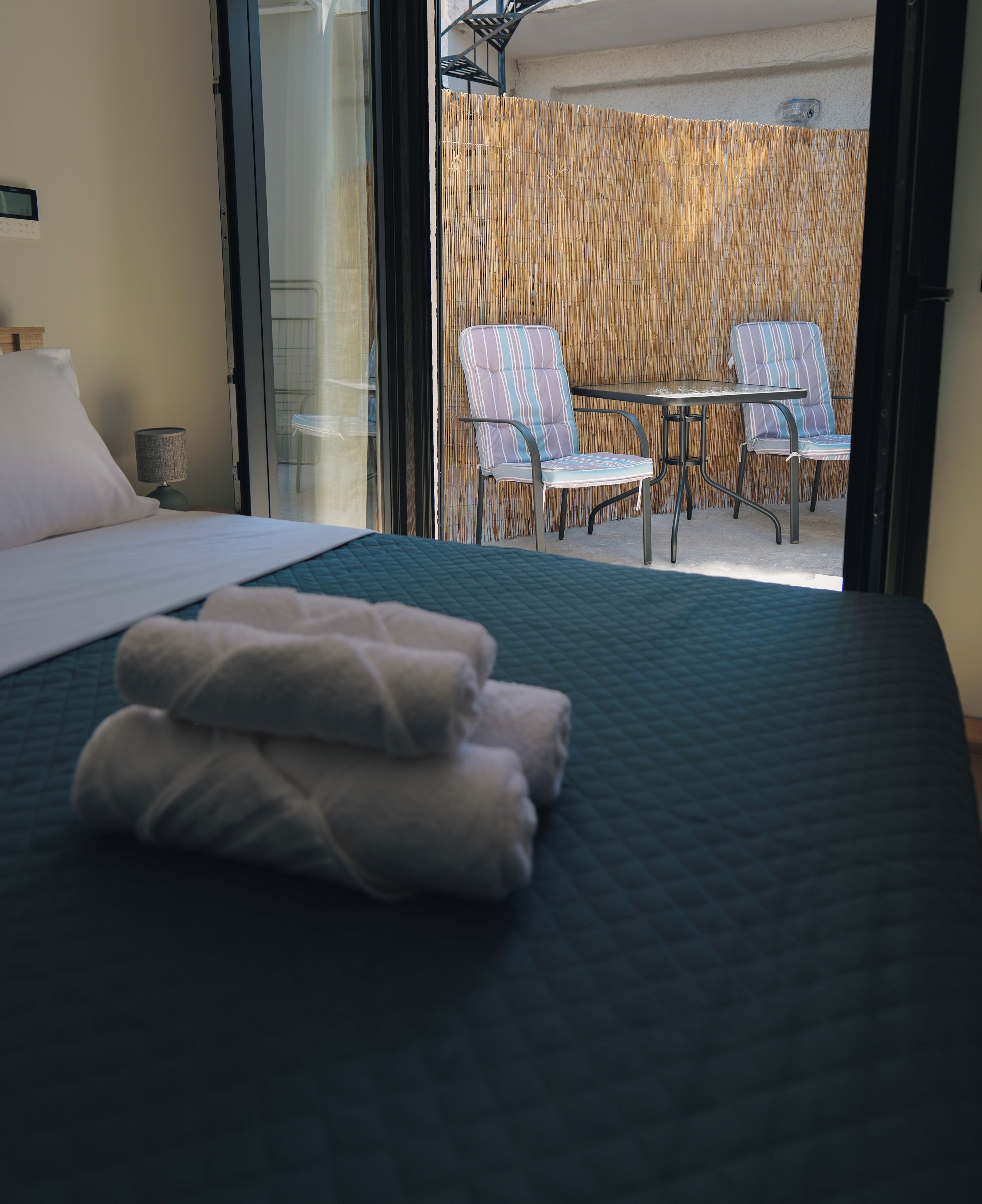 A hotel room with a bed, a table, and two chairs outside.