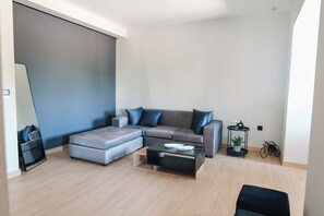 Una sala moderna con un sofá seccional gris, una mesa de centro y una mesita auxiliar con una planta.
