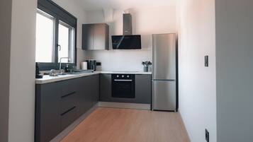 A compact kitchen with a built-in oven, a refrigerator, and a microwave.