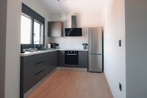 A compact kitchen with a built-in oven, a refrigerator, and a microwave.