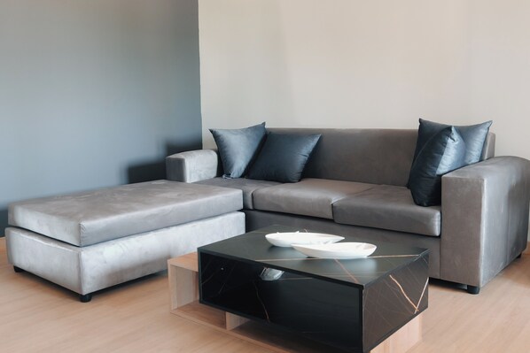 A modern living room with a grey sectional sofa, a black coffee table, and a wooden floor.