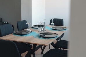 A dining table set with plates, cutlery, and glasses, surrounded by chairs.