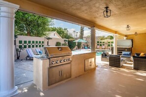 An outdoor patio with a built-in grill, seating area, and a pool. - FreePoolHeat|HotTub|Sleeps18|Arcade|ThemeRooms (Mesa)