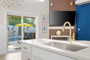 A modern kitchen with a large sink, a built-in stove, and a view of an outdoor pool area. - FreePoolHeat|HotTub|Sleeps18|Arcade|ThemeRooms (Mesa)