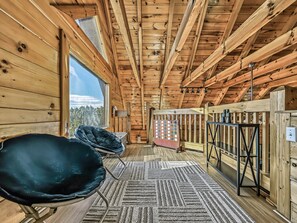 A wooden interior with a high ceiling, a black chair, a patterned rug, and a view through a window. - Mountain Views, 2 King Suites, Hot Tub, Cabin with AC in peaceful Sevierville (Sevierville)