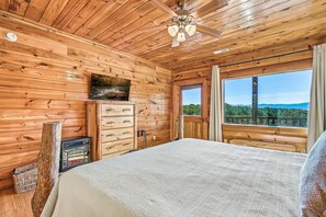 A wooden cabin bedroom with a bed, dresser, and a window with a view. - Mountain Views, 2 King Suites, Hot Tub, Cabin with AC in peaceful Sevierville (Sevierville)