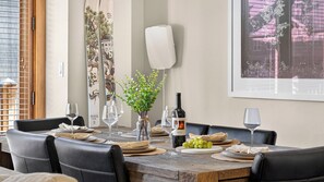 A dining table set with plates, glasses, a bottle of wine, and a small plant. - The Iron Horse by Avantstay Mountain Views Pool & Spa Walk to Gondola Skating Rink & Shops (Truckee)