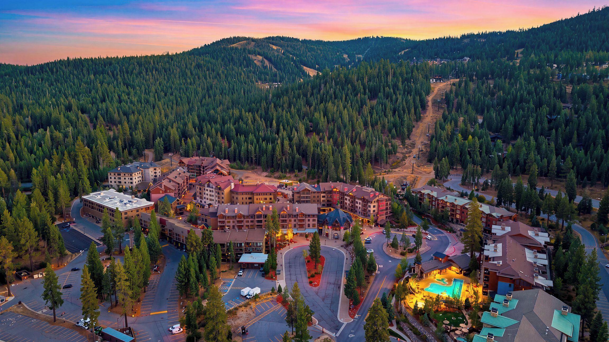 A resort with multiple buildings, a parking lot, and a swimming pool.