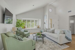 Una sala con sofá, dos sillones, una mesa de centro y una ventana con persianas.