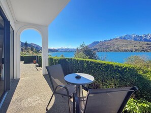 A balcony with a table and chairs overlooking a lake and mountains. - Private Genuine Lakefront Suite, Queenstown (Queenstown)