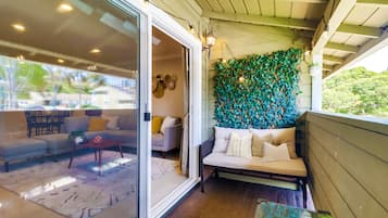 Un soggiorno moderno con una porta vetrata che si apre su una zona esterna, un divano con cuscini e una parete decorata con vegetazione verde.