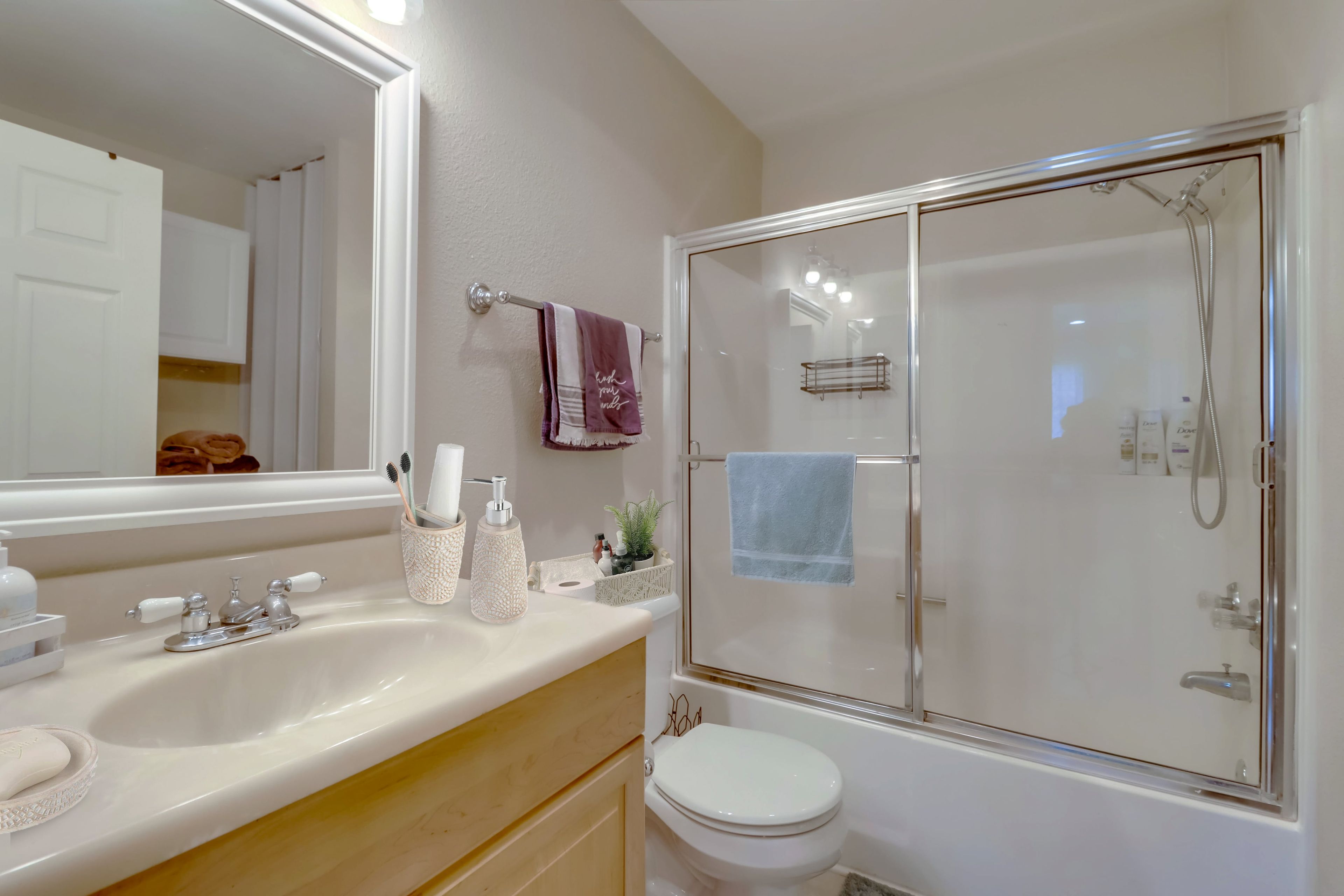 A bathroom with a white sink, a mirror, a toilet, and a glass-enclosed shower.