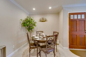 Un comedor con una mesa redonda, cuatro sillas, una planta en maceta y un adorno en la pared.