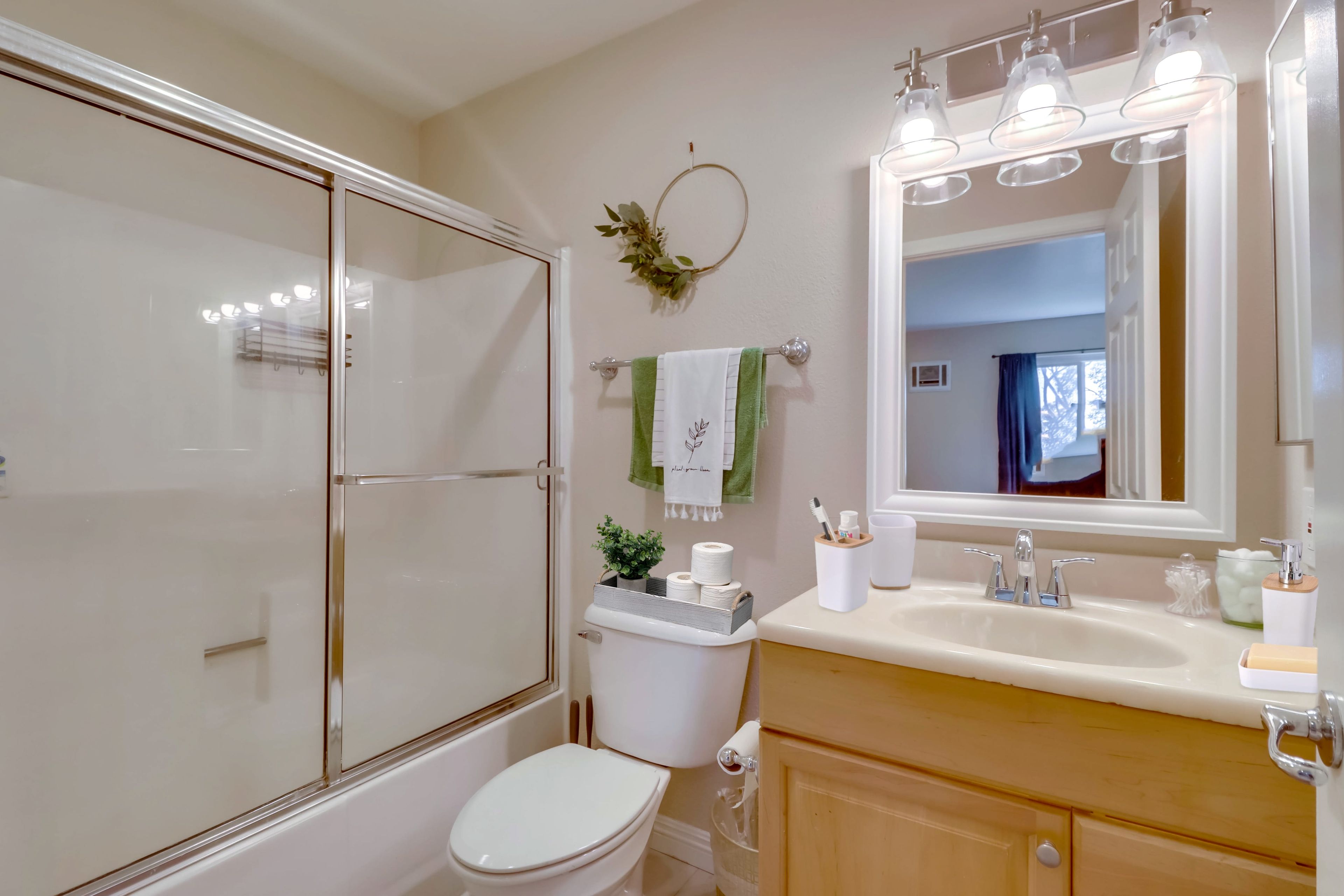 A bathroom with a glass shower enclosure, a toilet, a sink with a mirror, and a towel rack with towels.