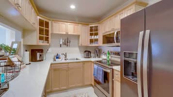 Eine moderne Küche mit Holzschränken, einem Edelstahlkühlschrank und einem eingebauten Backofen.